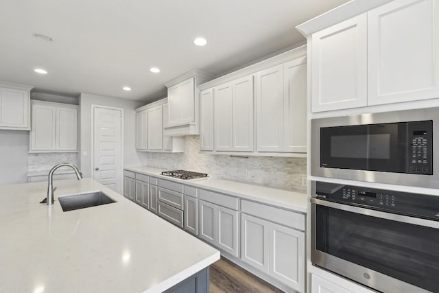 kitchen with sink, white cabinets, decorative backsplash, stainless steel appliances, and dark wood-type flooring