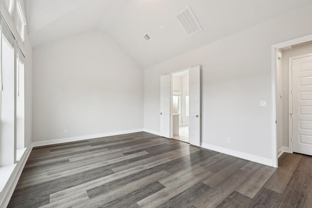 spare room with dark wood-type flooring and vaulted ceiling