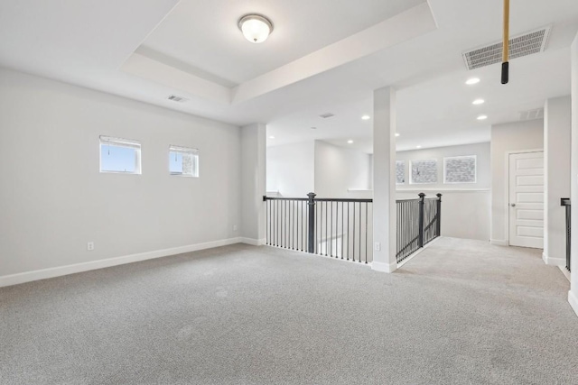 carpeted spare room featuring a raised ceiling