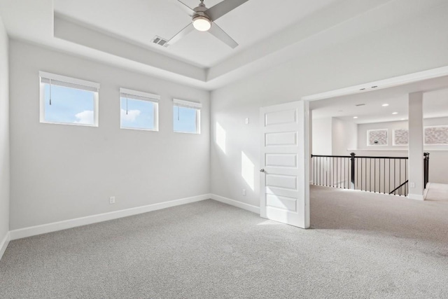 carpeted spare room featuring ceiling fan and a tray ceiling