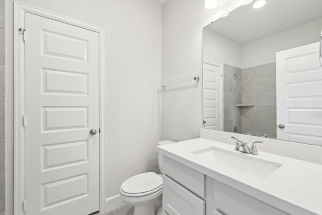 bathroom featuring vanity, toilet, and tiled shower