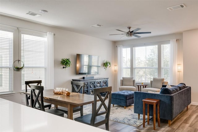 living room with a fireplace, ceiling fan, and light wood-type flooring