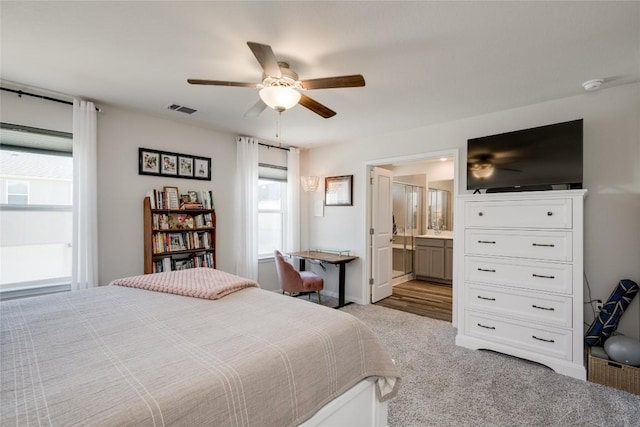 bedroom featuring ceiling fan, connected bathroom, light carpet, and multiple windows