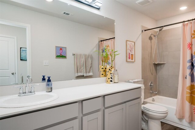 bathroom featuring toilet, shower / bath combination with curtain, visible vents, and vanity
