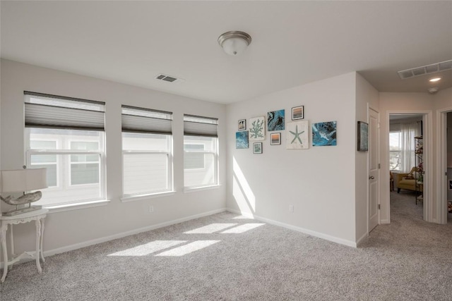 empty room featuring carpet flooring, visible vents, and baseboards