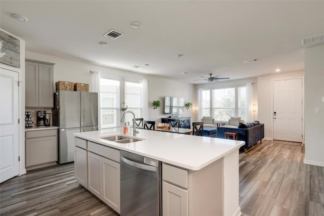 kitchen featuring sink, stainless steel appliances, a healthy amount of sunlight, and a center island with sink