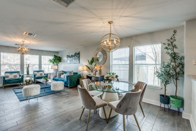 dining space with a wealth of natural light, hardwood / wood-style floors, and a notable chandelier