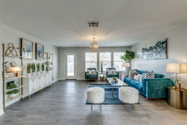 living room with an inviting chandelier, plenty of natural light, wood-type flooring, and a wood stove