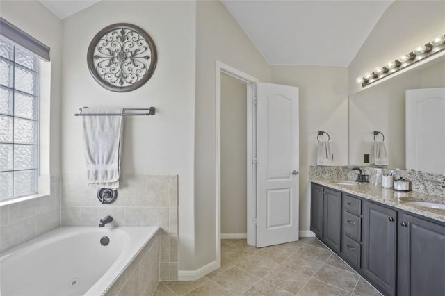 bathroom featuring lofted ceiling, tile patterned flooring, a wealth of natural light, and tiled bath