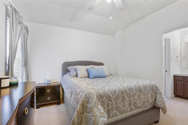 bedroom featuring ceiling fan, connected bathroom, vaulted ceiling, and light carpet