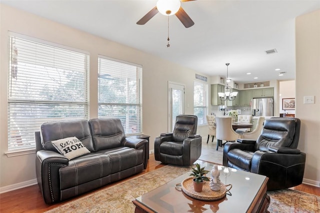 living room featuring ceiling fan with notable chandelier and wood-type flooring