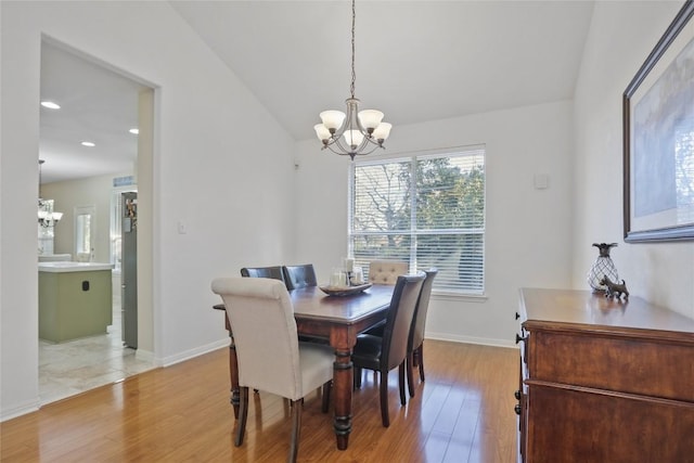 dining area featuring lofted ceiling, a notable chandelier, and light hardwood / wood-style floors