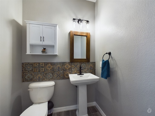 bathroom with wood-type flooring, toilet, and backsplash