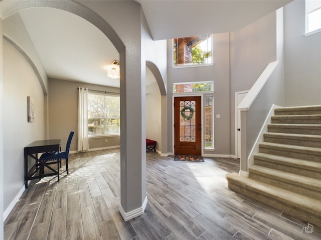 foyer entrance featuring wood-type flooring and a towering ceiling