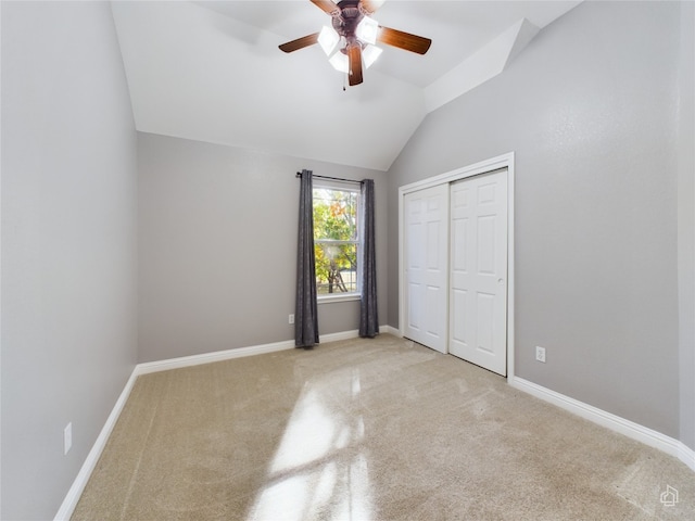 unfurnished bedroom with carpet floors, lofted ceiling, a closet, baseboards, and ceiling fan