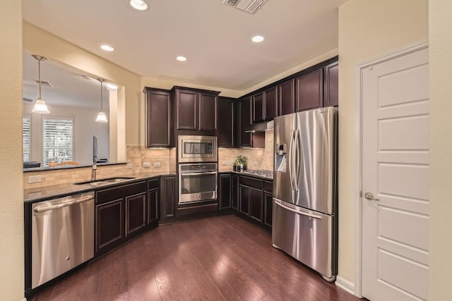 kitchen featuring hanging light fixtures, tasteful backsplash, appliances with stainless steel finishes, and dark wood-type flooring