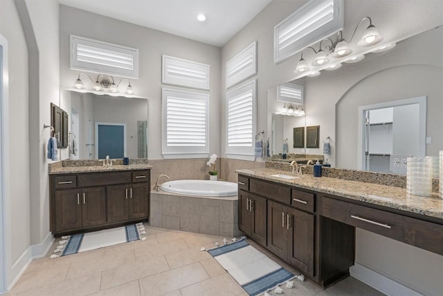 bathroom featuring tile patterned flooring, vanity, and tiled bath