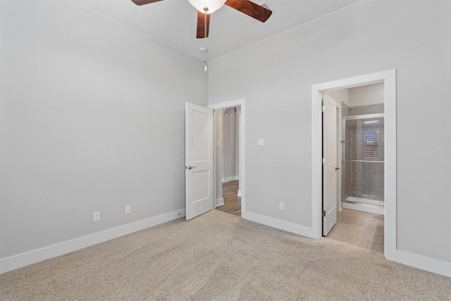 unfurnished bedroom featuring ceiling fan, light colored carpet, and ensuite bath