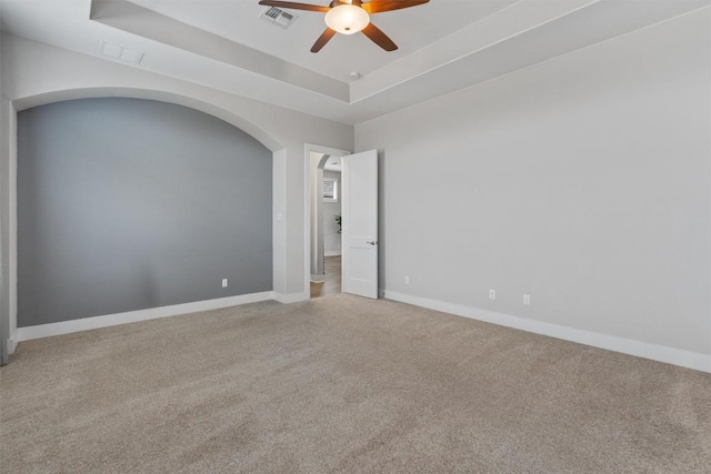 empty room featuring carpet floors, a raised ceiling, and ceiling fan