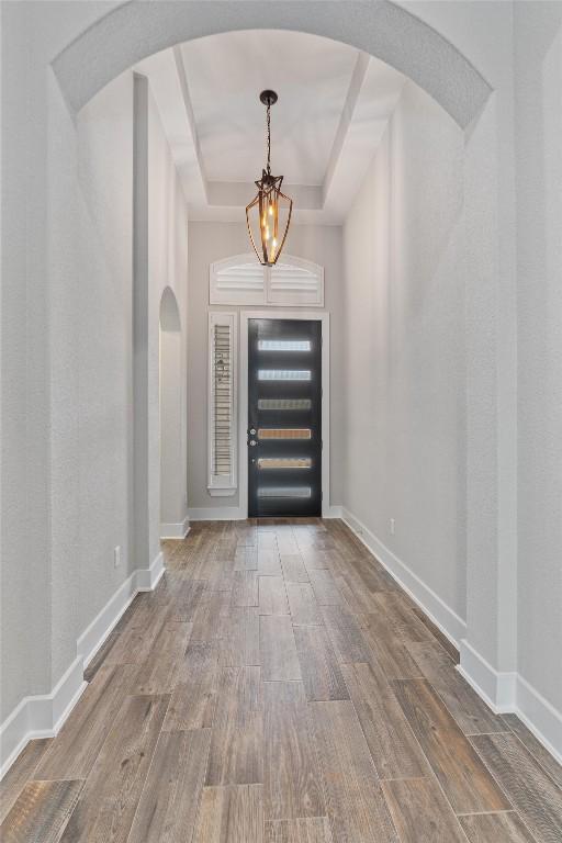 foyer with an inviting chandelier, a tray ceiling, and hardwood / wood-style flooring