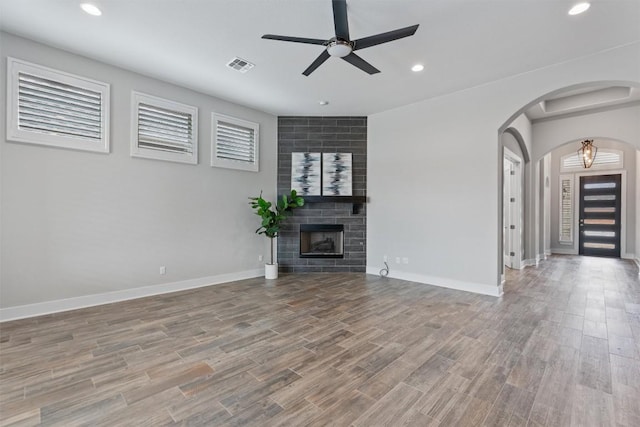 unfurnished living room featuring ceiling fan, a large fireplace, and light hardwood / wood-style floors