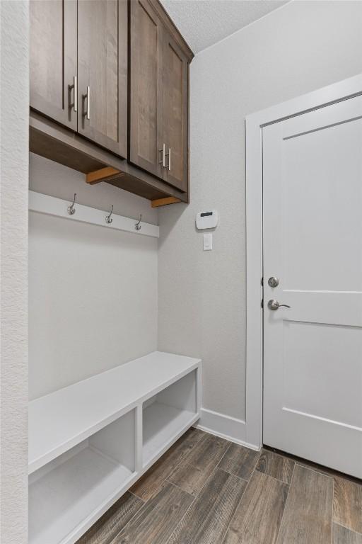 mudroom with dark wood-type flooring and a textured ceiling