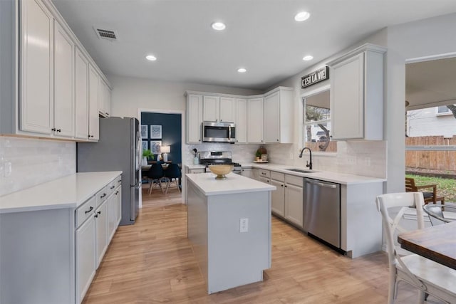 kitchen with stainless steel appliances, light countertops, visible vents, light wood-style flooring, and a kitchen island