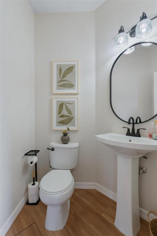 bathroom with wood finished floors, toilet, and baseboards