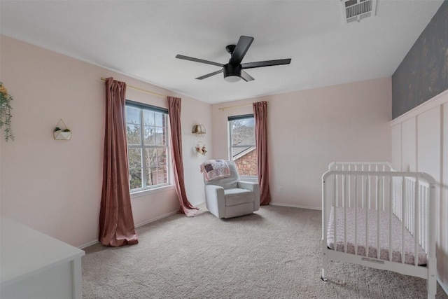 carpeted bedroom with a nursery area, visible vents, ceiling fan, and baseboards