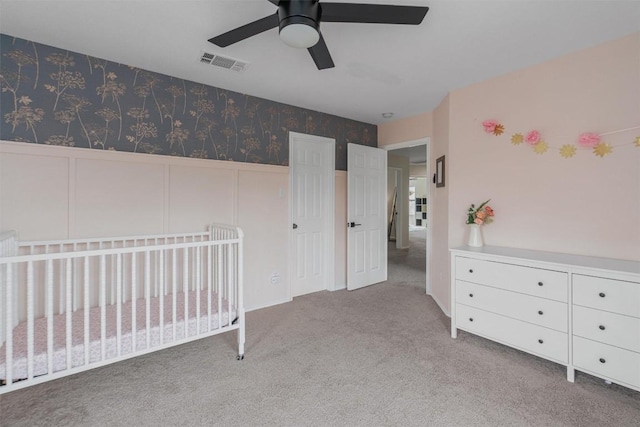 unfurnished bedroom featuring wallpapered walls, visible vents, wainscoting, carpet, and a decorative wall