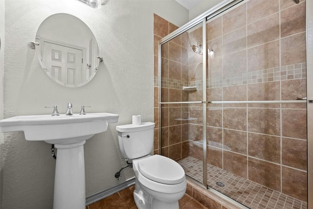 bathroom featuring toilet, tile patterned floors, and a shower with shower door