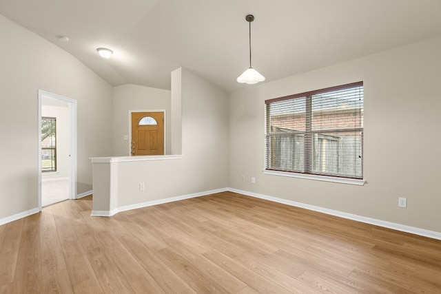 empty room with light wood-type flooring, vaulted ceiling, and a wealth of natural light