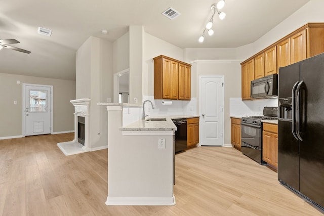 kitchen featuring kitchen peninsula, black appliances, light hardwood / wood-style floors, sink, and light stone counters