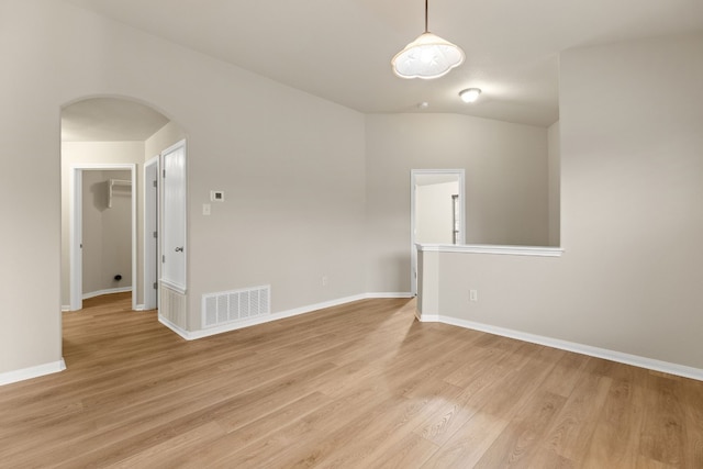 spare room with light hardwood / wood-style flooring and vaulted ceiling