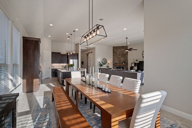 dining area featuring sink, a large fireplace, and ceiling fan