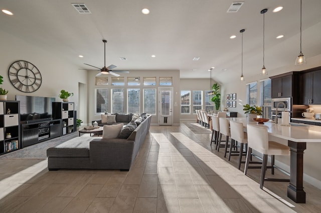 living room featuring sink, vaulted ceiling, and ceiling fan