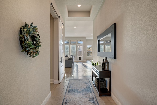 corridor featuring a barn door and a raised ceiling