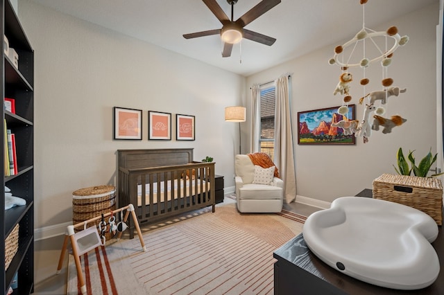 bedroom with a nursery area and ceiling fan