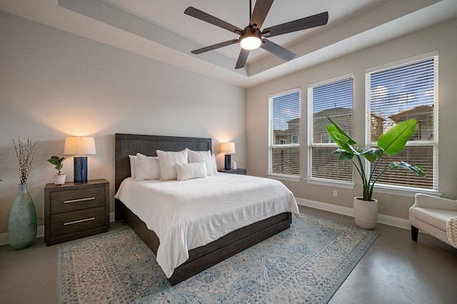 bedroom with a raised ceiling, concrete flooring, and ceiling fan