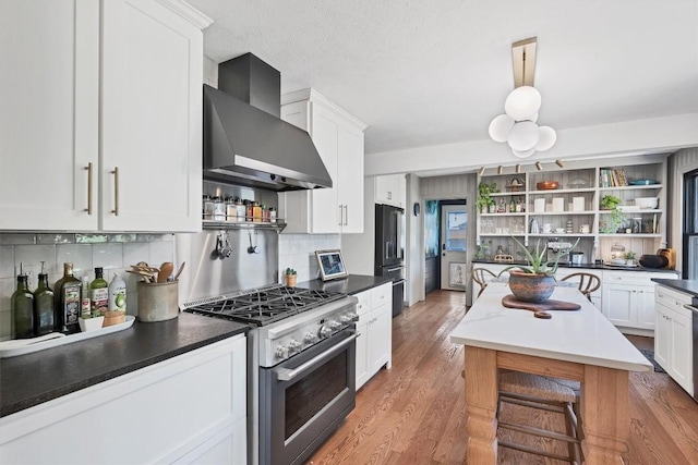 kitchen with white cabinetry, wood-type flooring, premium appliances, and wall chimney exhaust hood