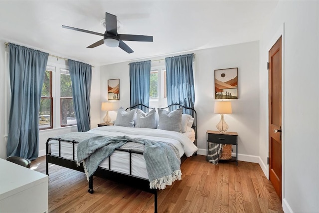 bedroom with multiple windows, light hardwood / wood-style floors, and ceiling fan