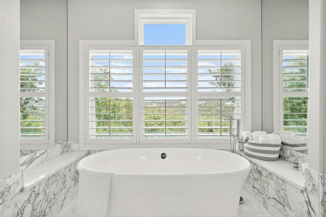 full bathroom featuring marble finish floor and a freestanding tub