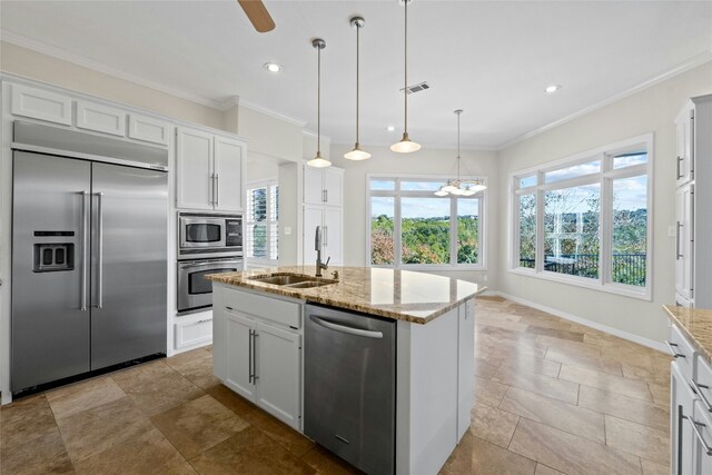 kitchen with sink, built in appliances, hanging light fixtures, a kitchen island with sink, and white cabinets