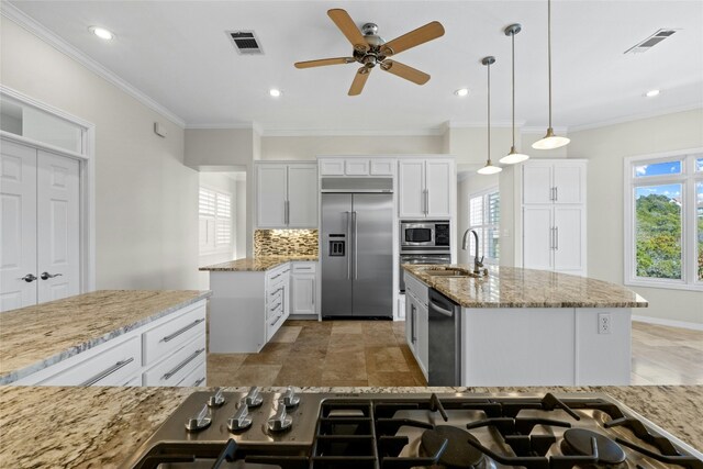 kitchen featuring white cabinetry, built in appliances, an island with sink, and hanging light fixtures