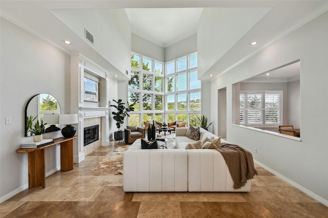 living area featuring a wealth of natural light, a towering ceiling, visible vents, and baseboards