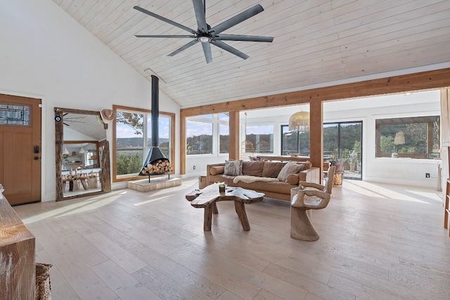 living room featuring ceiling fan, high vaulted ceiling, light hardwood / wood-style flooring, and a wood stove