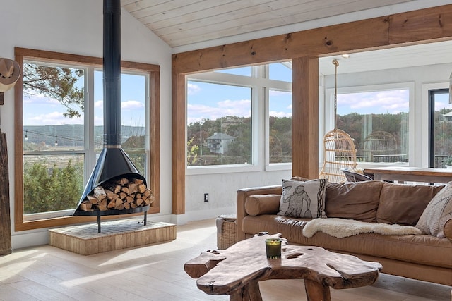 sunroom / solarium featuring vaulted ceiling, a wood stove, and wood ceiling