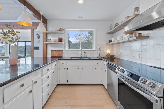 kitchen with sink, appliances with stainless steel finishes, white cabinetry, extractor fan, and decorative backsplash