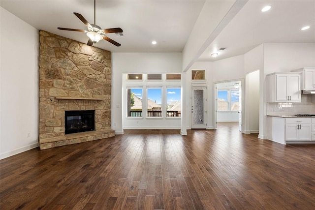 unfurnished living room with ceiling fan, a fireplace, plenty of natural light, and dark hardwood / wood-style flooring