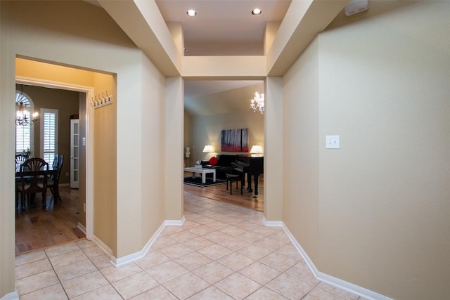 corridor with an inviting chandelier and light tile patterned flooring